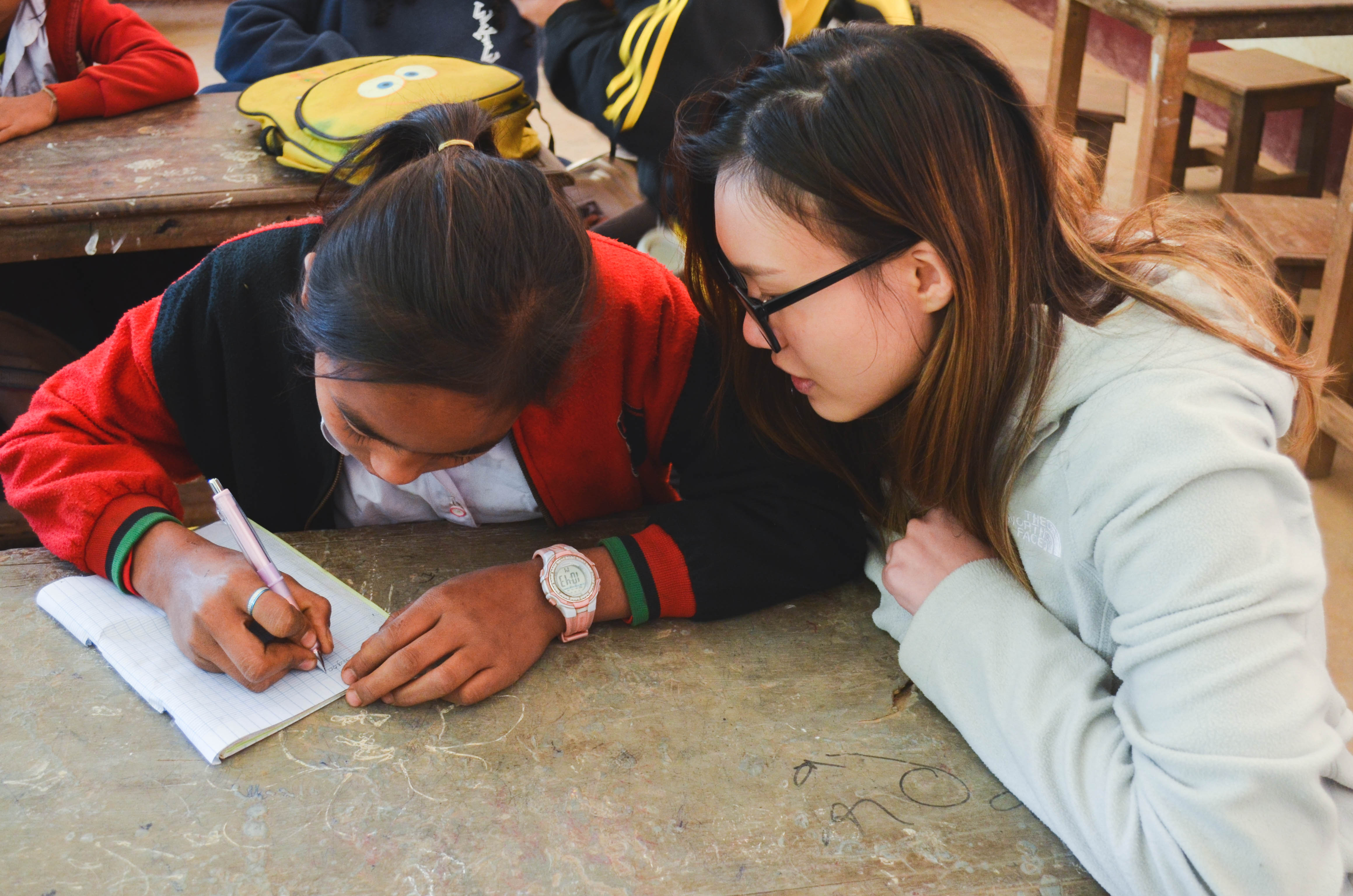 Our volunteer, Gaelmaine, watching as the children jot down what they had learned in class that day.