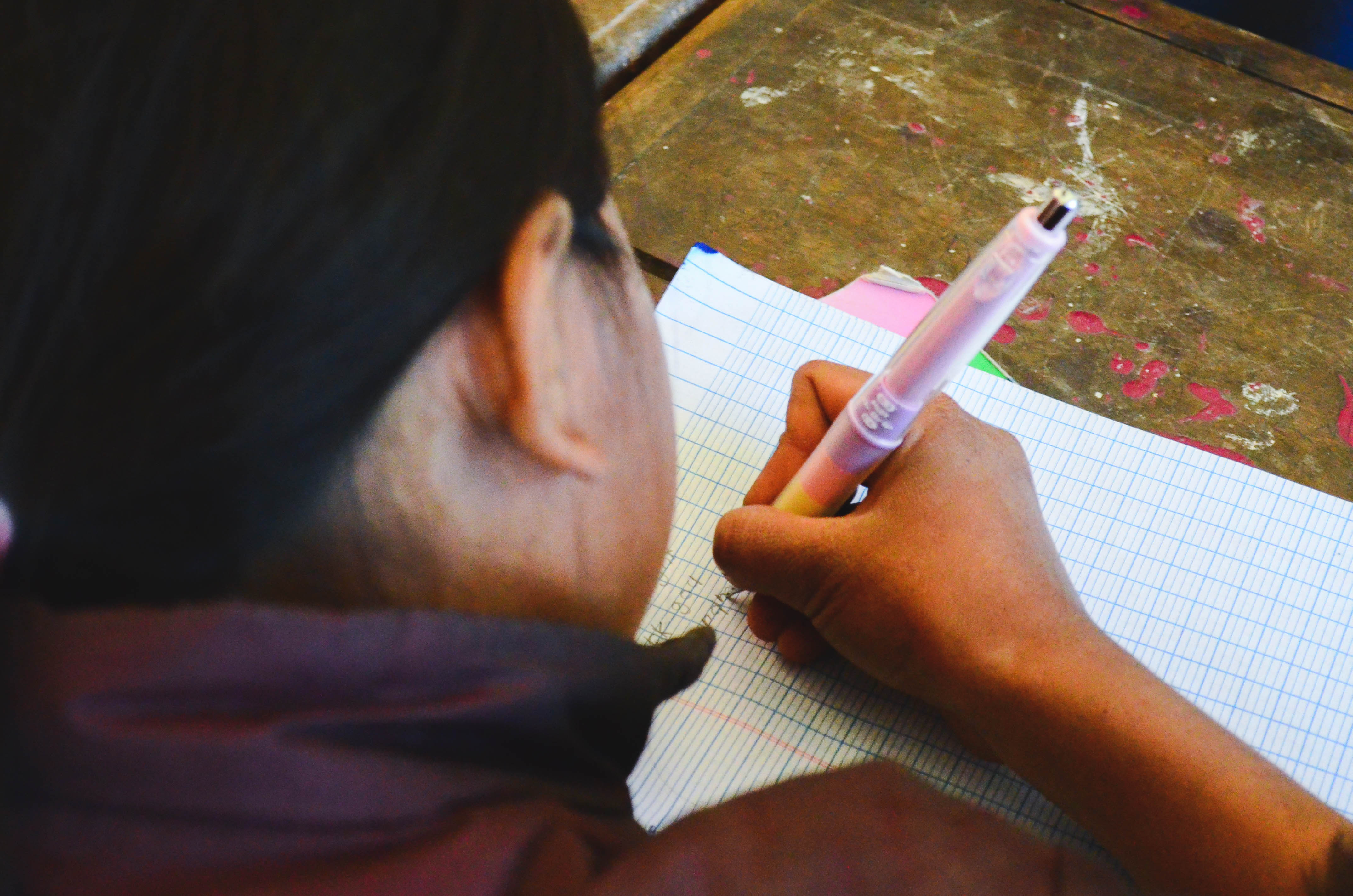 One of the children writing in their notebooks with a pen from Pilot! 