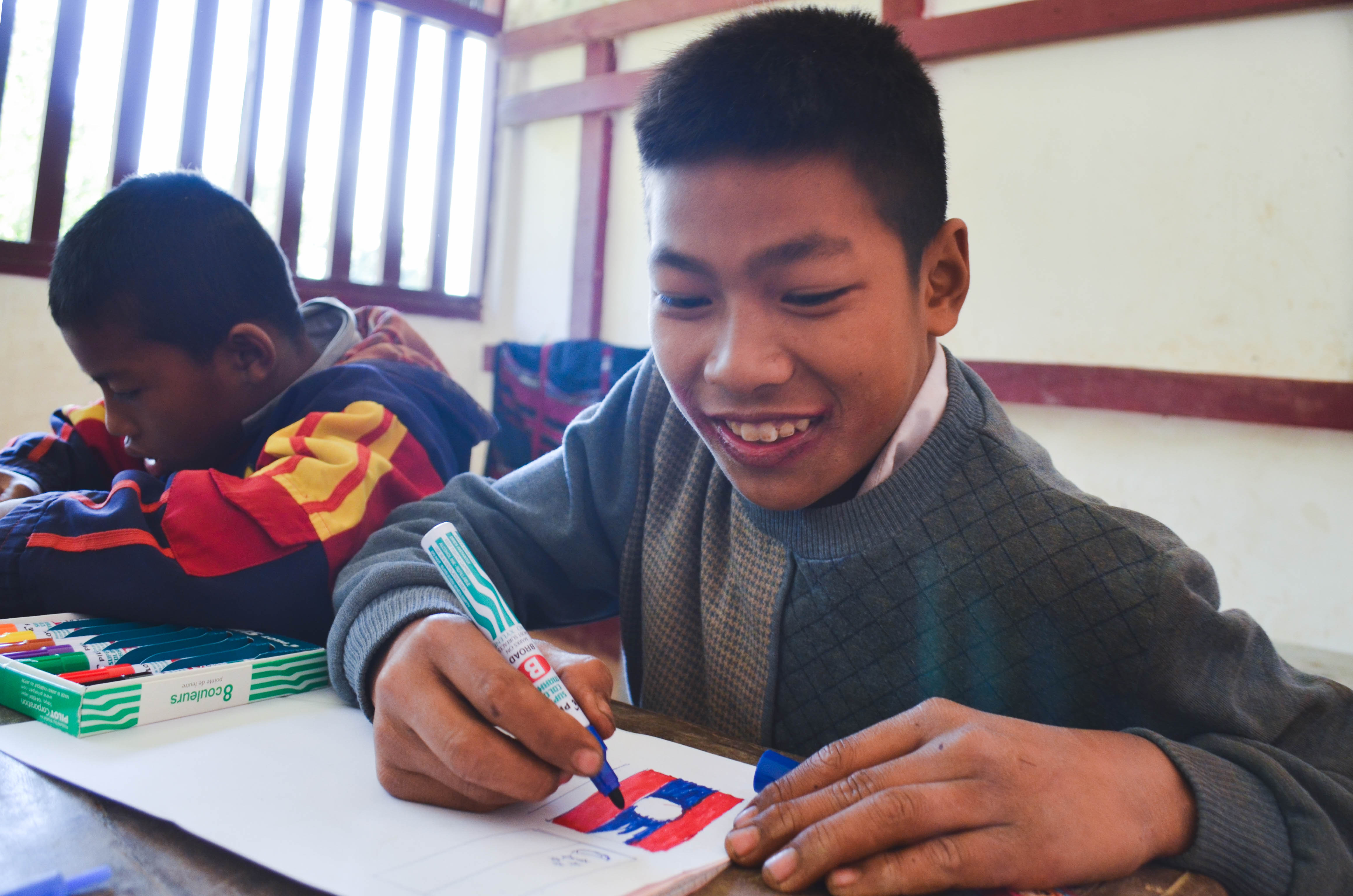 A big smile from Set as he colours in the Lao flag with markers from Pilot!