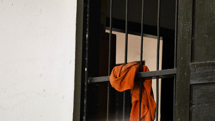 A monk's orange robes hangs from a window.